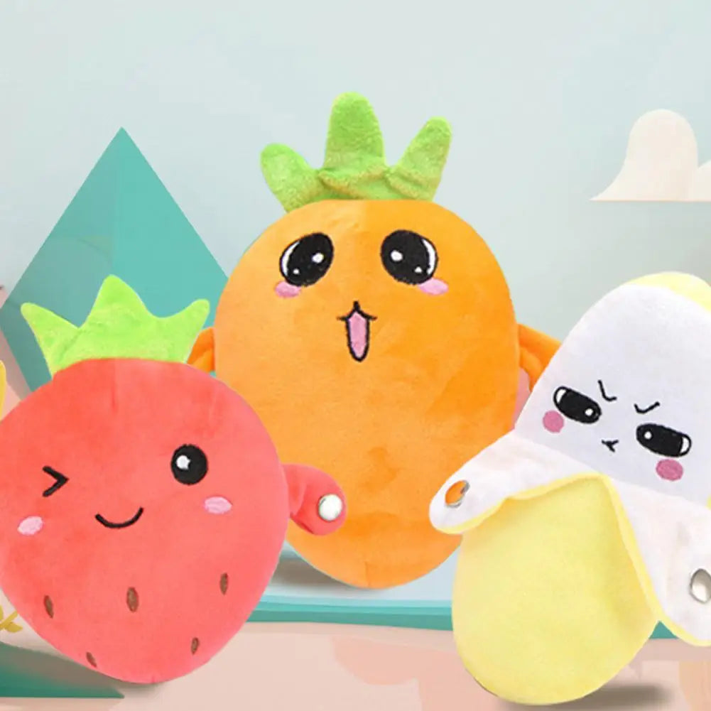 An orange plush toy shaped like a fruit, a red strawberry plush, and a yellow banana plush are displayed against a light blue