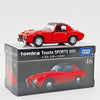 A red Tomica Toyota Sports 800 die-cast model car displayed in its packaging box.