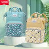 A light blue mommy backpack with a patterned fabric and a yellow mommy backpack displayed on a white stand.