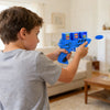 A boy is holding and aiming a blue soft foam flying disc launcher toy for kids.