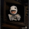 A plush doll wearing a white hood and dark features is displayed inside a wooden box.
