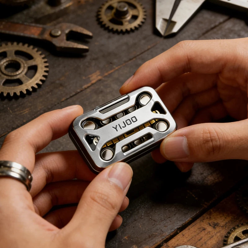 A hand holds a silver metal magnetic fidget slider device against a dark wooden background.