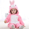 A baby wearing a pink bunny hooded romper with white accents sitting on a white surface.