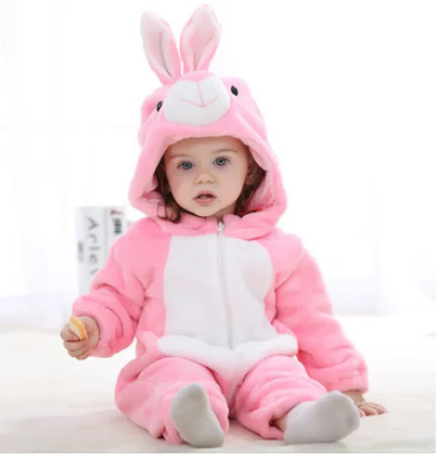 A baby wearing a pink bunny hooded romper with white accents sitting on a white surface.