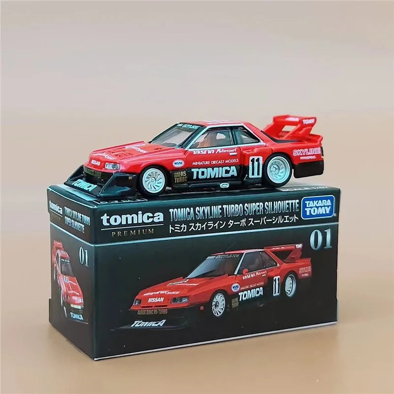 A red and black Tomica scale model sports car kit displayed in its packaging box.