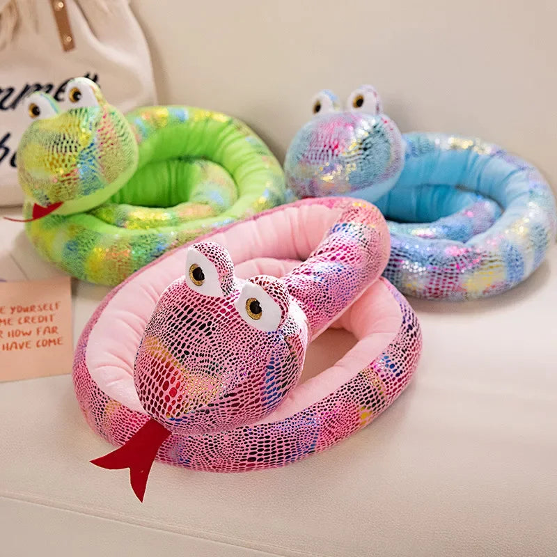 A collection of colorful, squiggly plush snake toys in various shades of green, blue, and pink are displayed on a light surfa