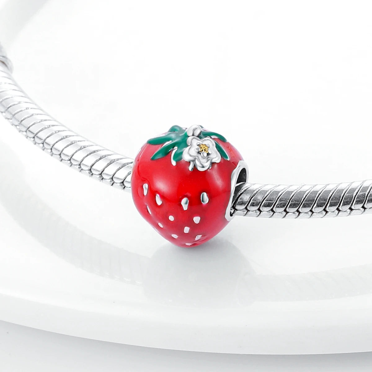 A red strawberry charm bead made of 925 sterling silver with a zircon detail, displayed on a white surface.