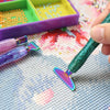 A hand holds a sparkly resin diamond painting pen with an interchangeable metal tip on a light gray surface.