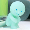 A small, light blue glow-in-the-dark figurine of a person sitting down.