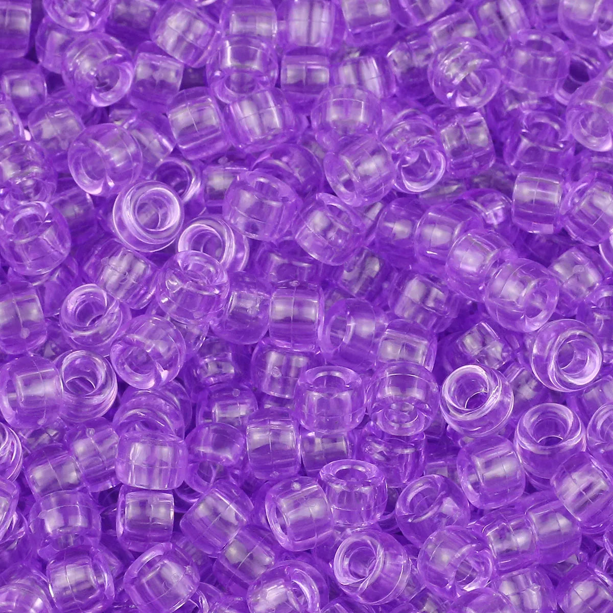A close-up view of small, translucent purple pony beads for jewelry making and craft projects.