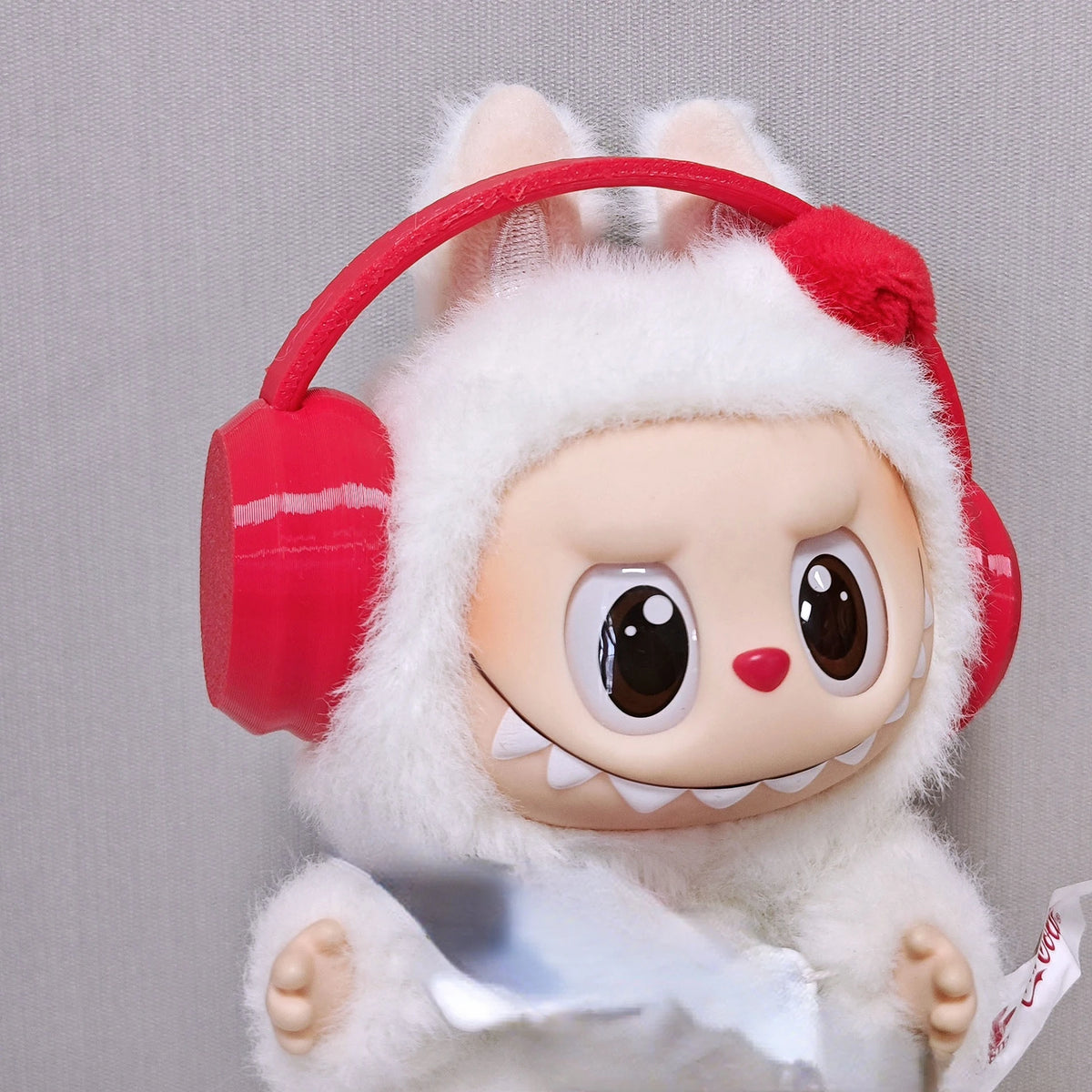 Labubu doll wearing a white hoodie and red headphones