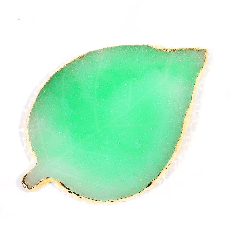 A translucent green resin nail art palette with a gold trim, shaped like a leaf.