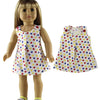 A doll wearing a white top with a colorful heart pattern and a matching skirt.