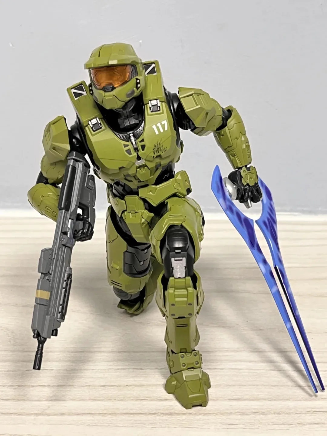 A 1/12 scale Master Chief action figure in olive green armor standing on a wooden surface.