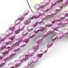 A string of purple heart-shaped acrylic beads for jewelry making laid out on a white background.