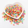 A white bowl filled with colorful polymer clay sprinkles for slime and craft decor, scattered around the bowl.