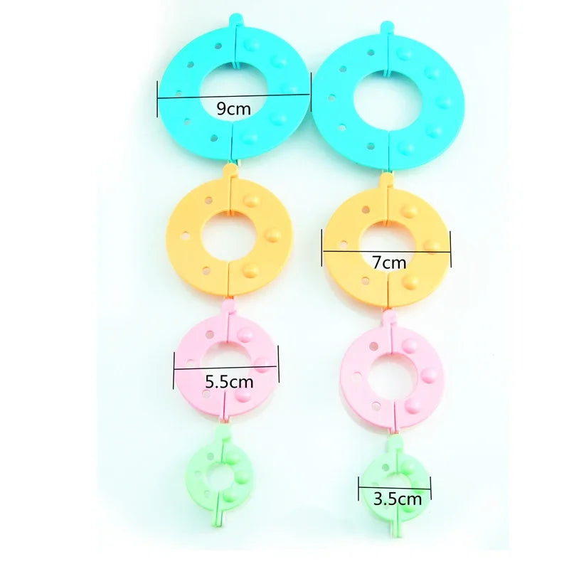 An assortment of eight plastic pom-pom maker rings in various colors and sizes, including light blue, yellow, pink, and green
