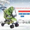 A green and black stroller with a transparent waterproof cover is shown in a snowy outdoor setting.