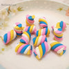 A collection of colorful polymer clay marshmallow charms in striped designs arranged on a white plate.