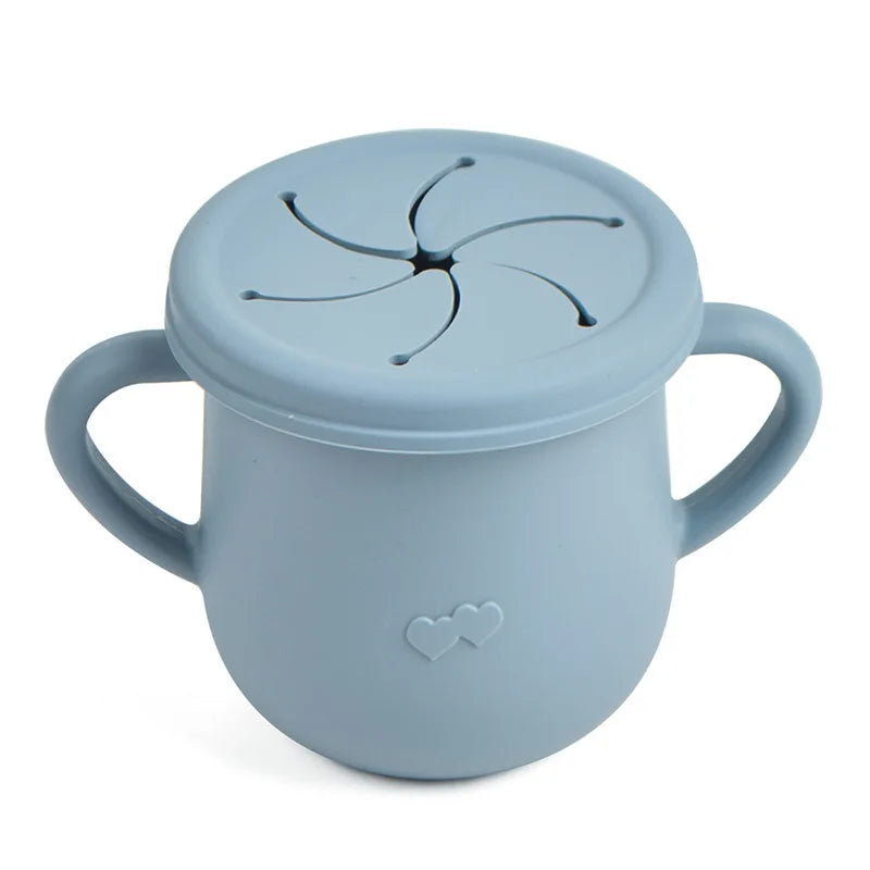 A light blue silicone snack cup with a lid and handle, featuring a decorative heart design.