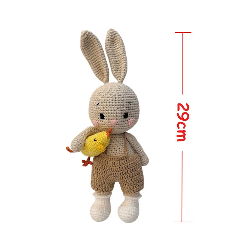 Handmade crochet stuffed bunny toy with long ears and a small yellow chick, displayed next to a measurement line.
