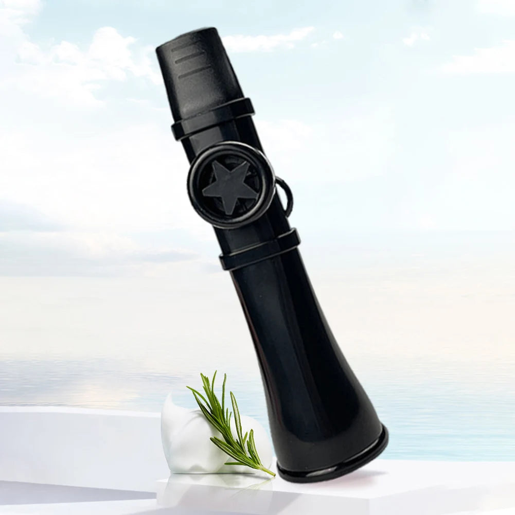 A black portable kazoo flute with a lanyard is shown against a light blue sky and water, resting on a white surface.