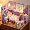 A detailed wooden miniature dollhouse kit featuring pink and white furniture and decor.