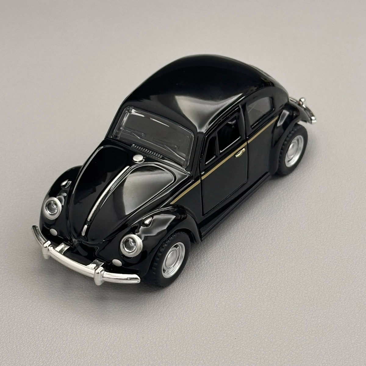 A glossy black classic retro Beetle diecast model car with chrome accents and a gold stripe.
