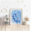 A framed picture of blue butterflies swimming in clear water displayed on a white wall.