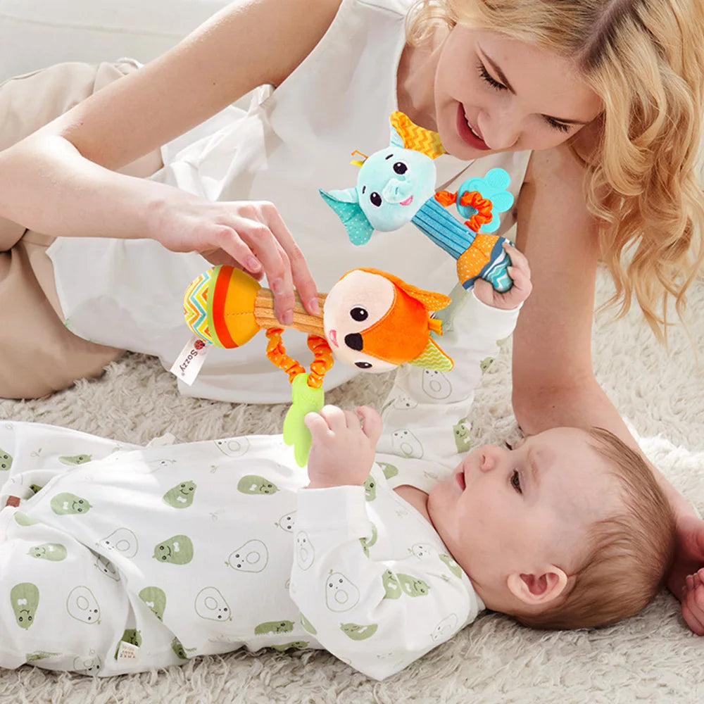 A woman is showing a baby a soft plush rattle toy set with crinkle and squeak sounds.