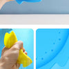 A hand is squeezing a yellow silicone splash flying ring toy into blue water.