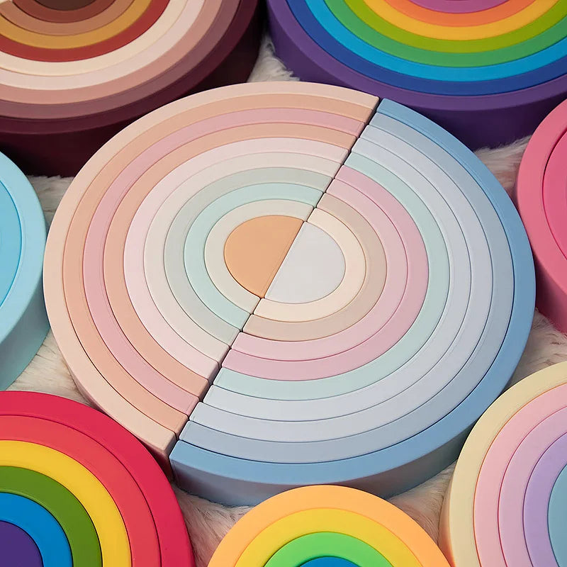 A close-up of soft silicone rainbow building blocks in various pastel colors arranged in a circular pattern.