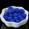 A white bowl filled with bright blue acrylic pearl beads for jewelry making