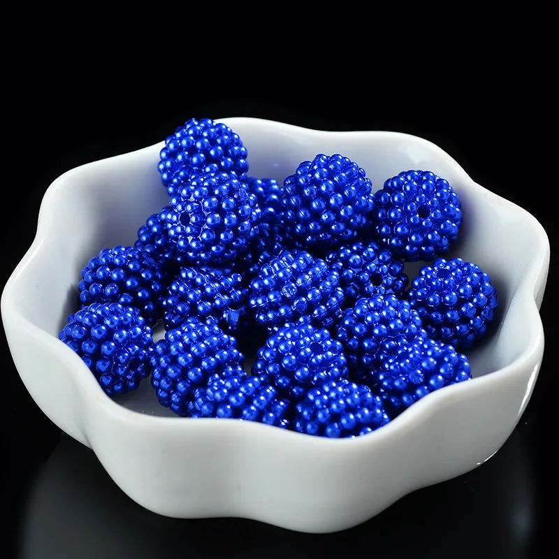 A white bowl filled with bright blue acrylic pearl beads for jewelry making