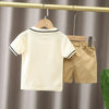 A beige boys' cotton summer short sleeve t-shirt and shorts set hanging on a wooden hanger.