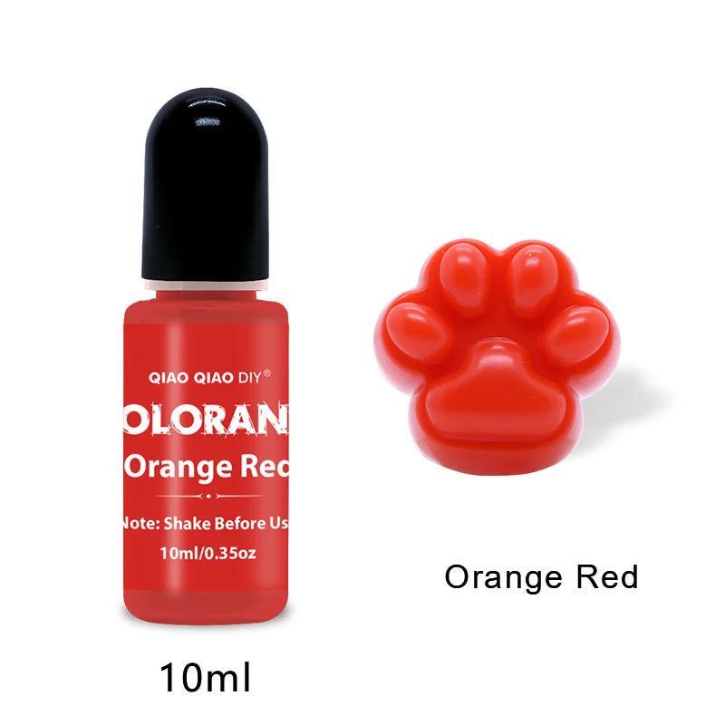 A small glass bottle of orange red liquid pigment with a black cap and a handprint shaped dye is shown next to a red paw prin