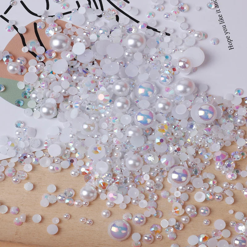 A pile of mixed resin rhinestone pearls with an AB finish scattered on a wooden surface.