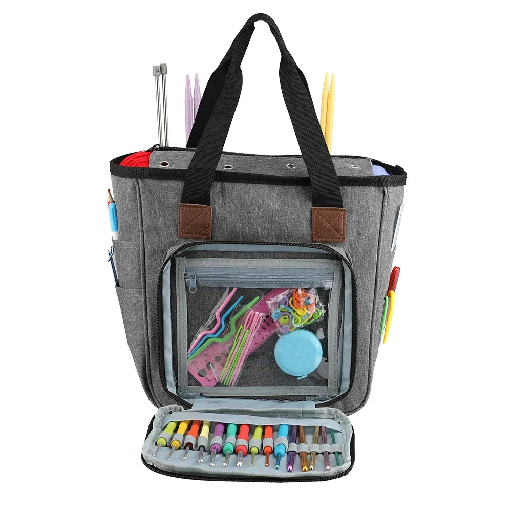 A gray canvas tote bag with organizer pockets and a clear window showing various knitting tools and supplies.