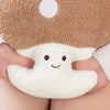 A hand is holding a white mushroom plush toy with brown eyes and a fuzzy beige background.