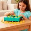 Une jeune fille assemble un puzzle 3D vert pour enfants sur une table en bois.