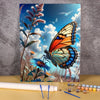 A painting in progress showing a vibrant orange and blue butterfly on a floral canvas against a bright blue sky.