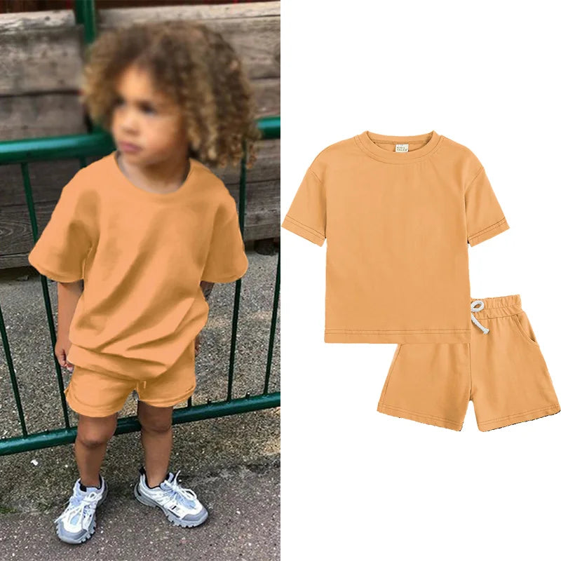 A child wearing a tan short sleeve top and matching shorts outdoors, shown next to the clothing items.