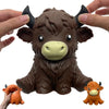 A brown squishy stress ball shaped like a Highland cow with horns and a light yellow snout being held by hands.