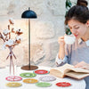 Une femme savoure un café devant une table blanche avec des sous-verres à motifs de fruits.