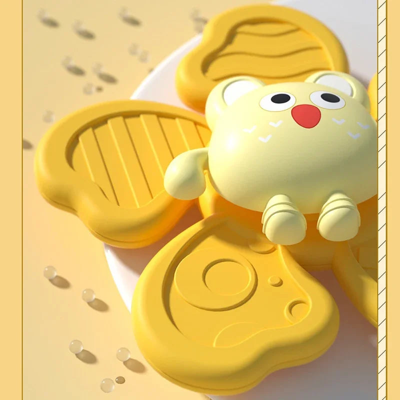 A yellow suction cup spinner bath toy shaped like a cute bear is shown on a light background.