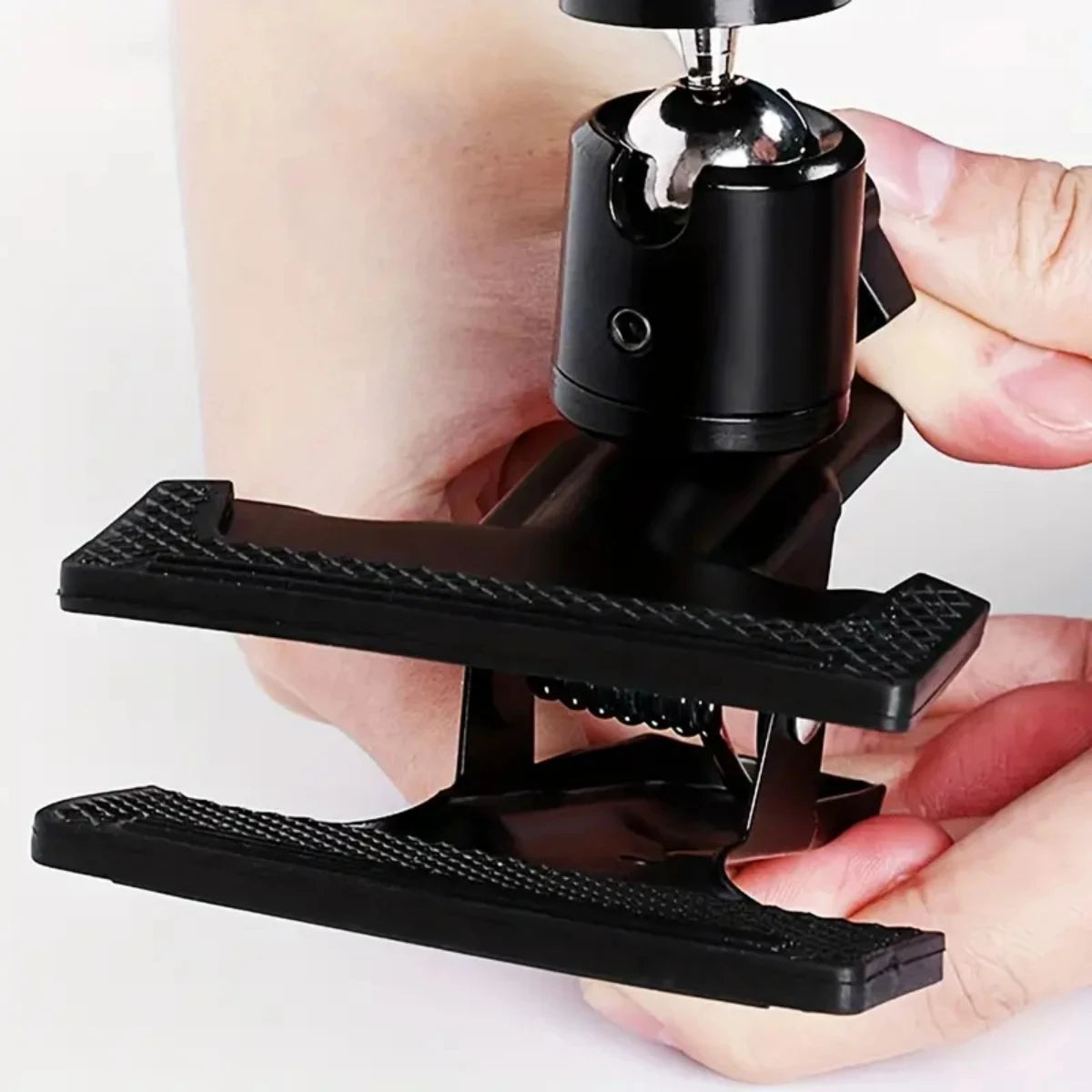 A hand holds a black 360° rotating guitar phone mount for live streaming and recording.