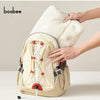 A beige baby windproof cape blanket with a white fluffy trim and dinosaur design is being held by a hand.