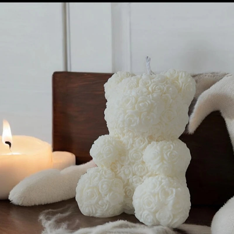 A white silicone mold shaped like a fluffy bear is shown next to a lit candle.