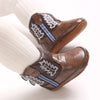 A close-up of brown baby western booties with white embroidery and blue stitching on a white sock.