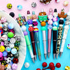 A collection of colorful 15mm printed silicone beads and various tools for DIY jewelry making arranged on a light pink backgr